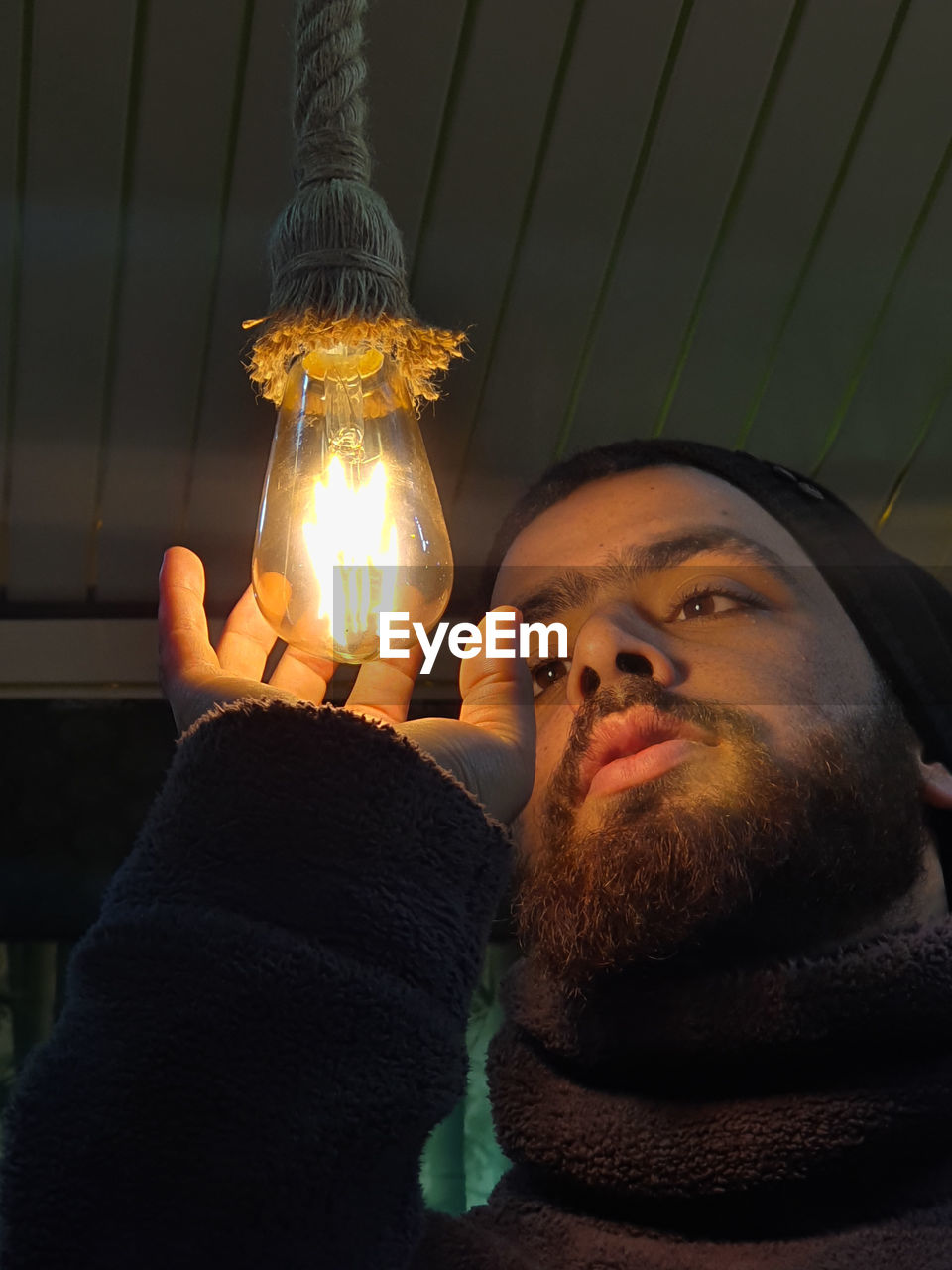 Close-up of young man holding illuminated lighting equipment