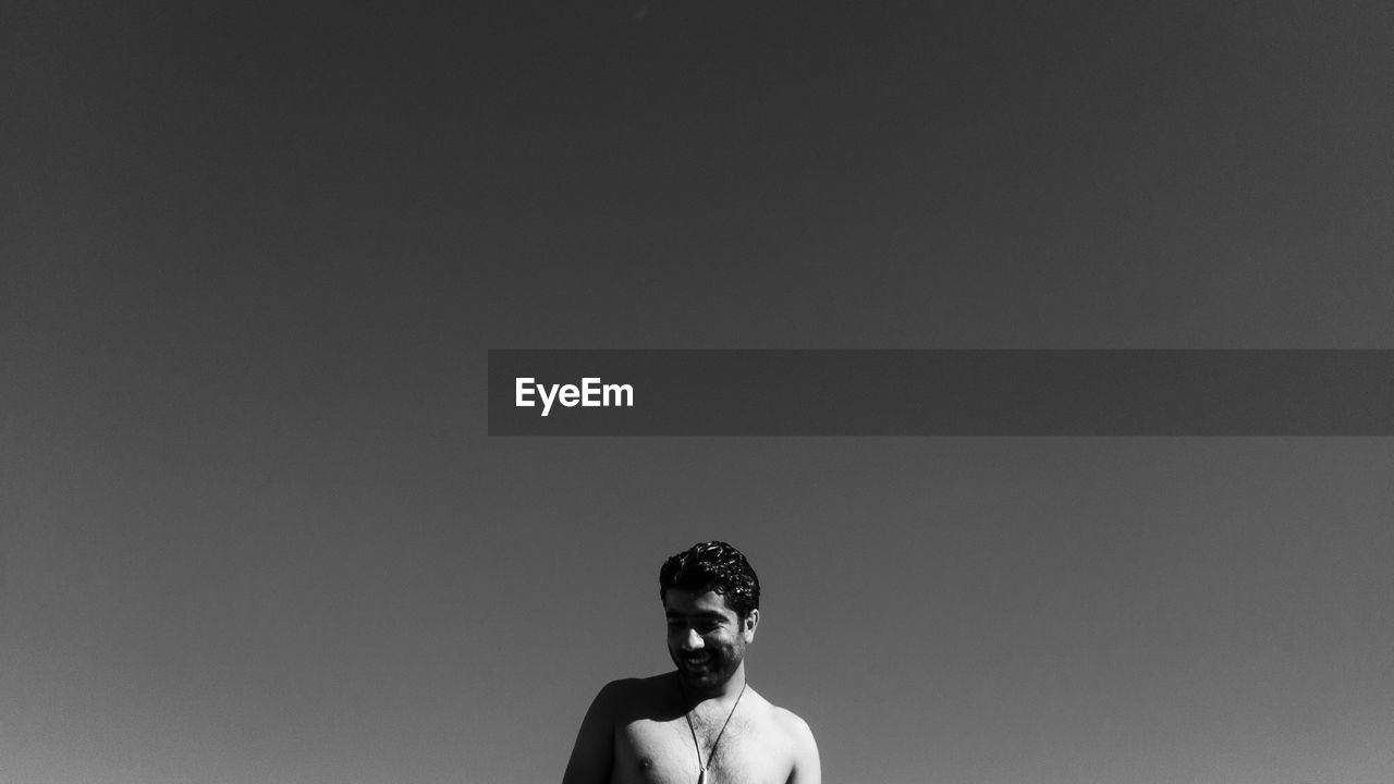PORTRAIT OF SHIRTLESS MAN AGAINST CLEAR SKY