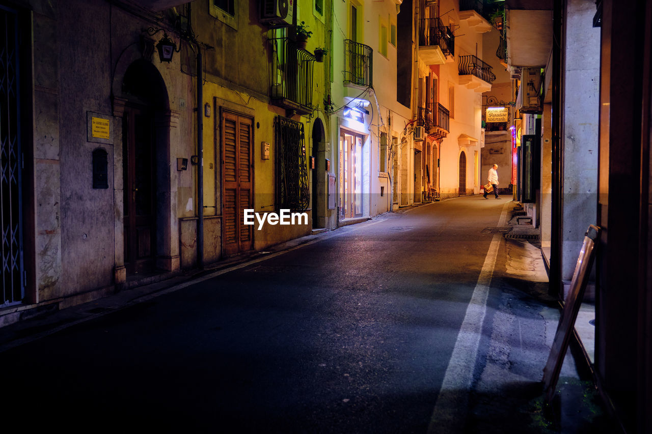 Narrow street amidst buildings in city at night