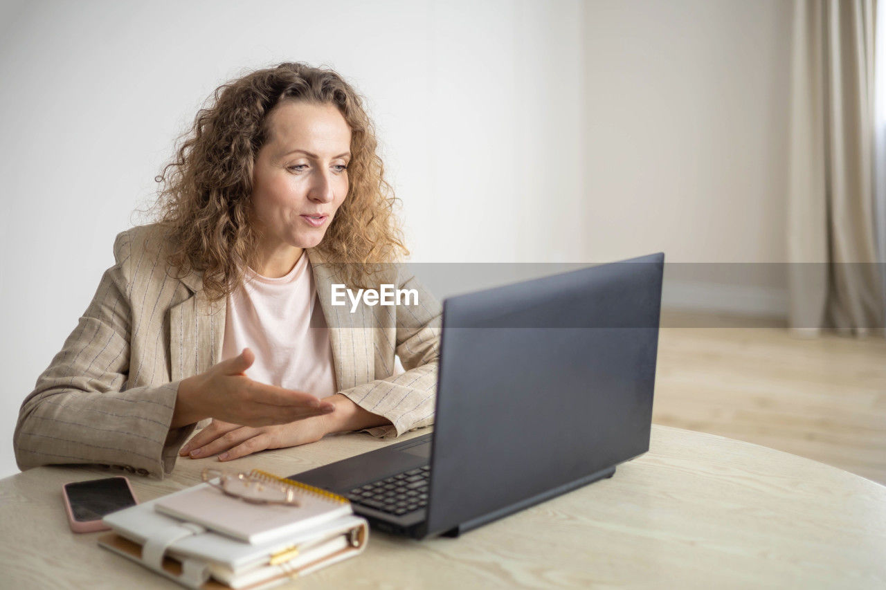 young woman using laptop while sitting on table