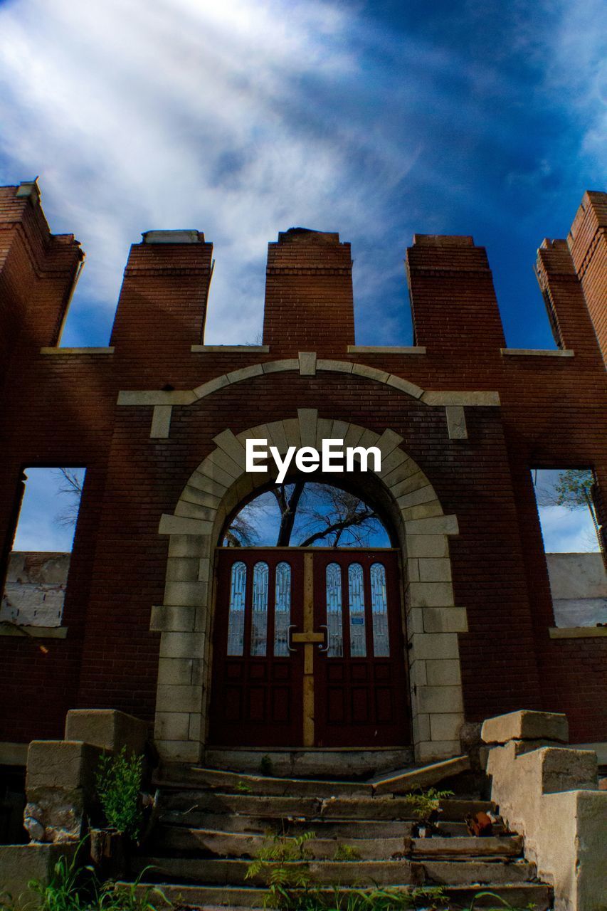 Low angle view of abandoned building against sky on sunny day