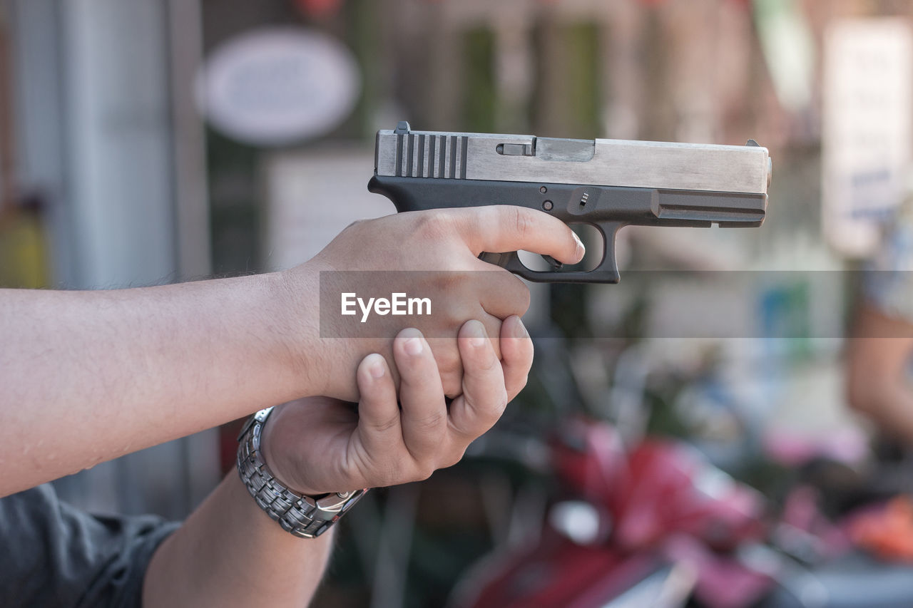 Cropped hand of man holding gun