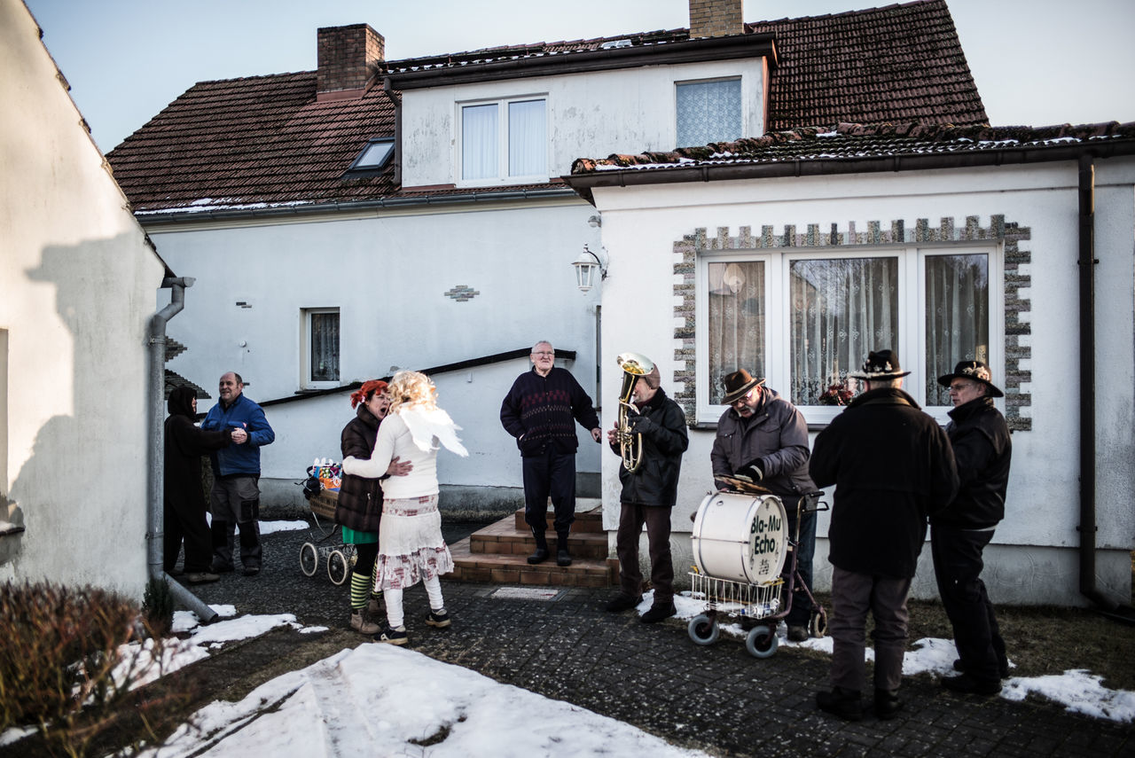 PEOPLE STANDING ON HOUSE AGAINST SKY