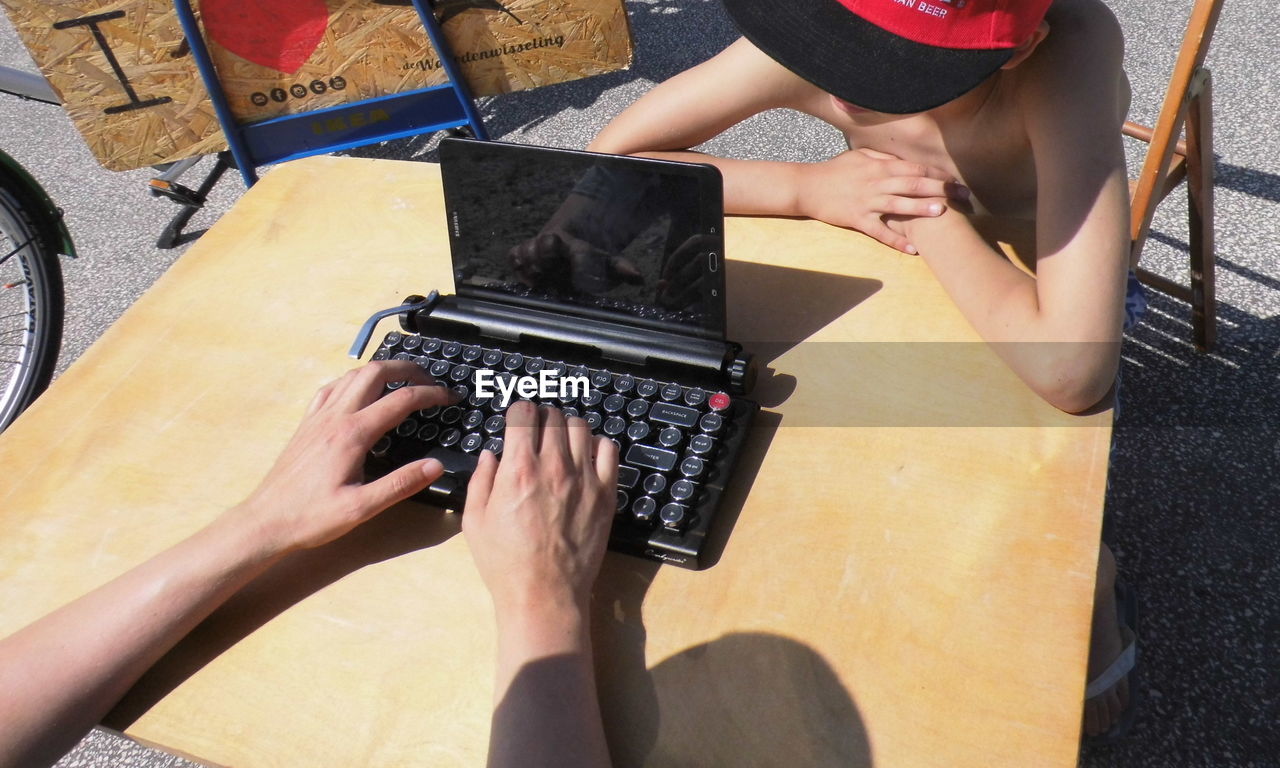 Hands typing on a very special laptop formed as a classic typewriter 