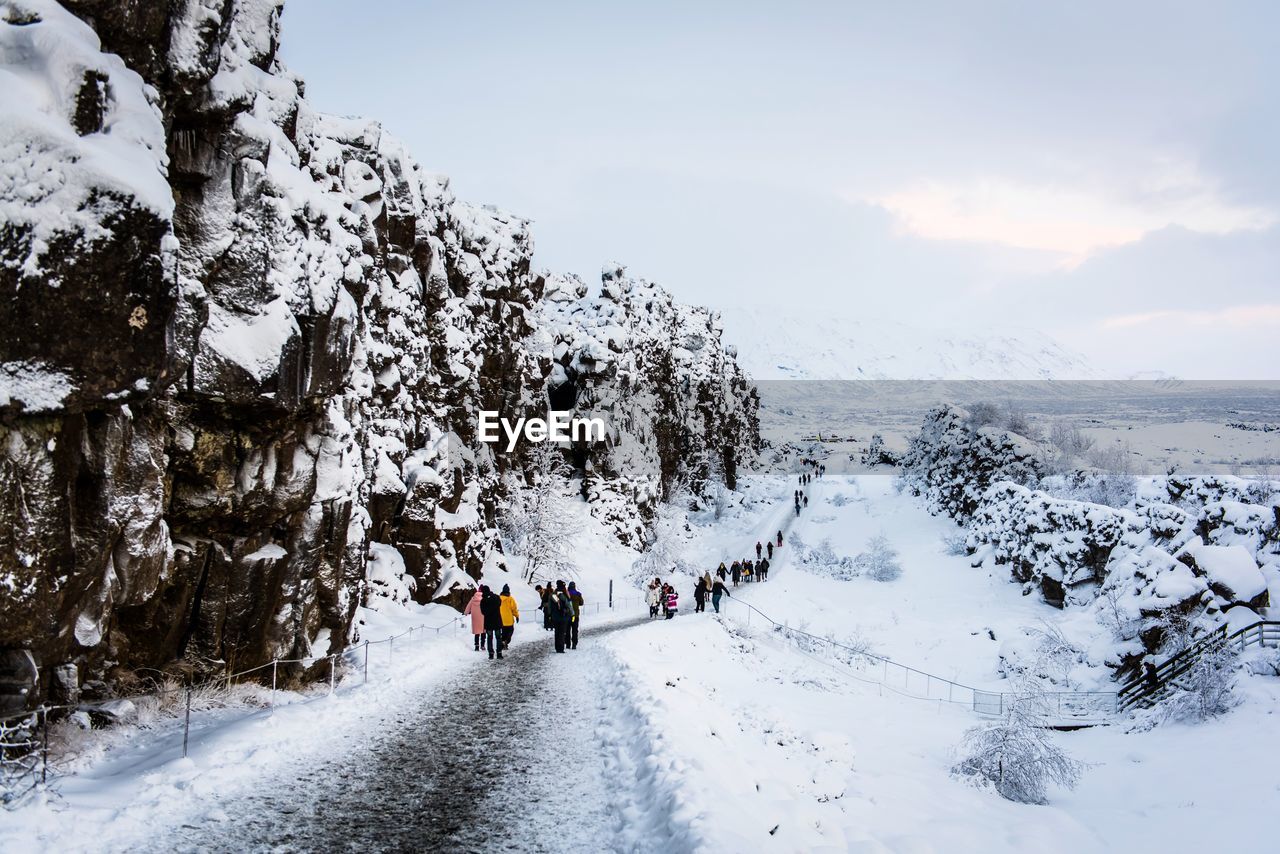 REAR VIEW OF PEOPLE WALKING ON SNOW COVERED MOUNTAIN