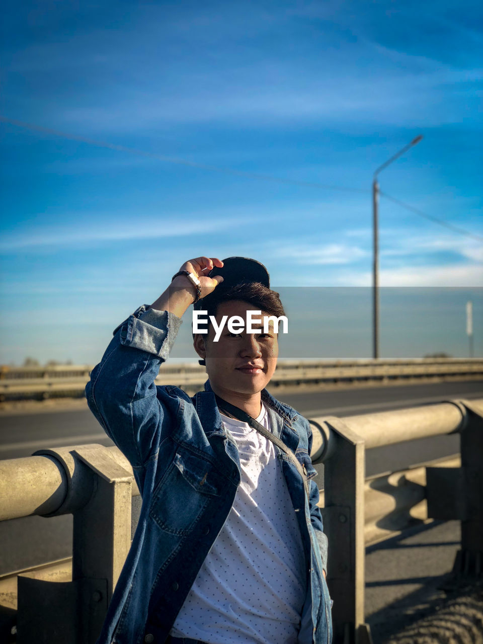 Young man looking away while standing against sky