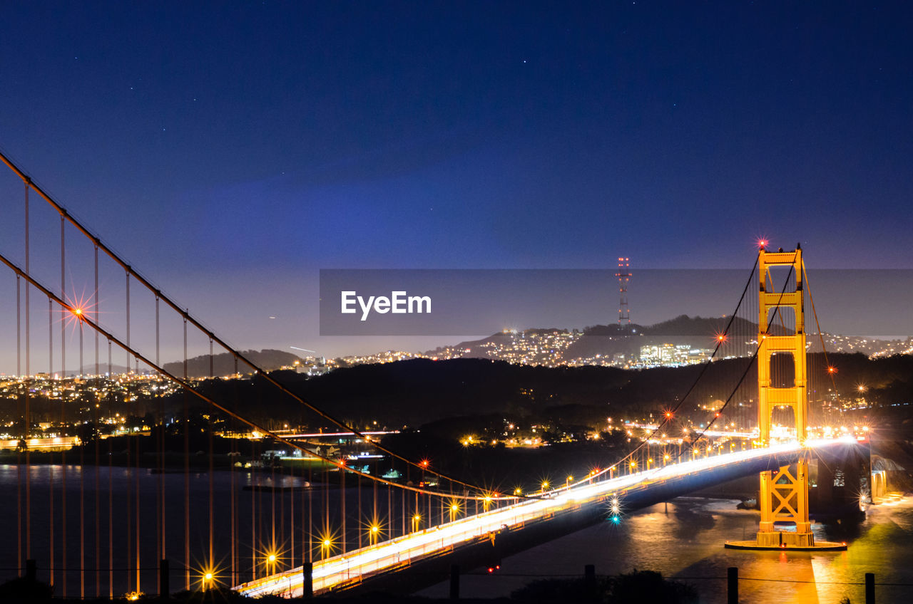 Illuminated suspension bridge over river at night