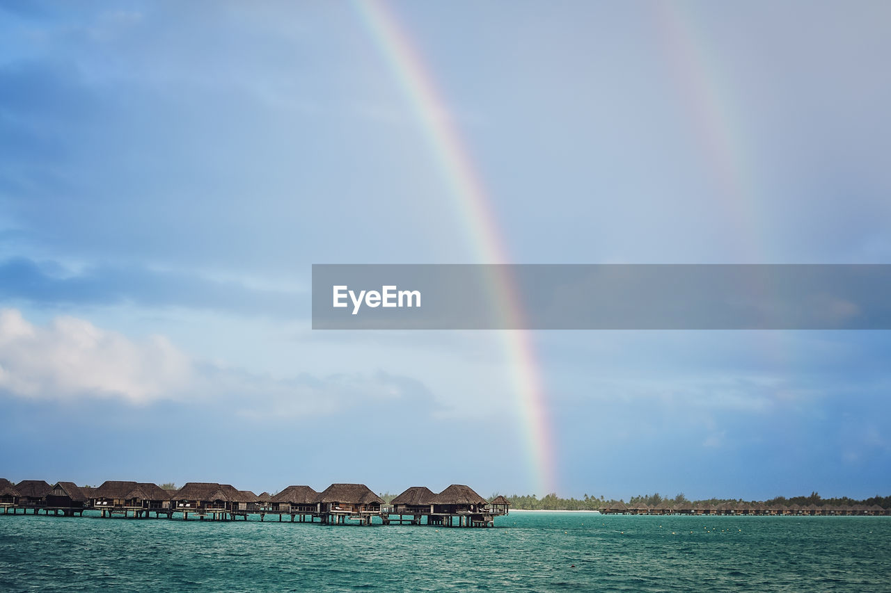 Double rainbow over huts in bora bora - huts in the ocean - rainbow after a storm