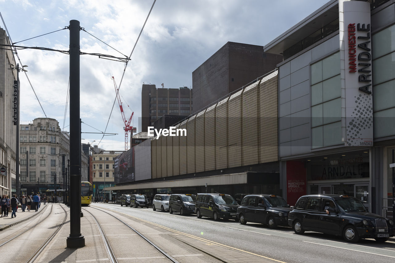 CARS ON ROAD BY BUILDINGS AGAINST SKY