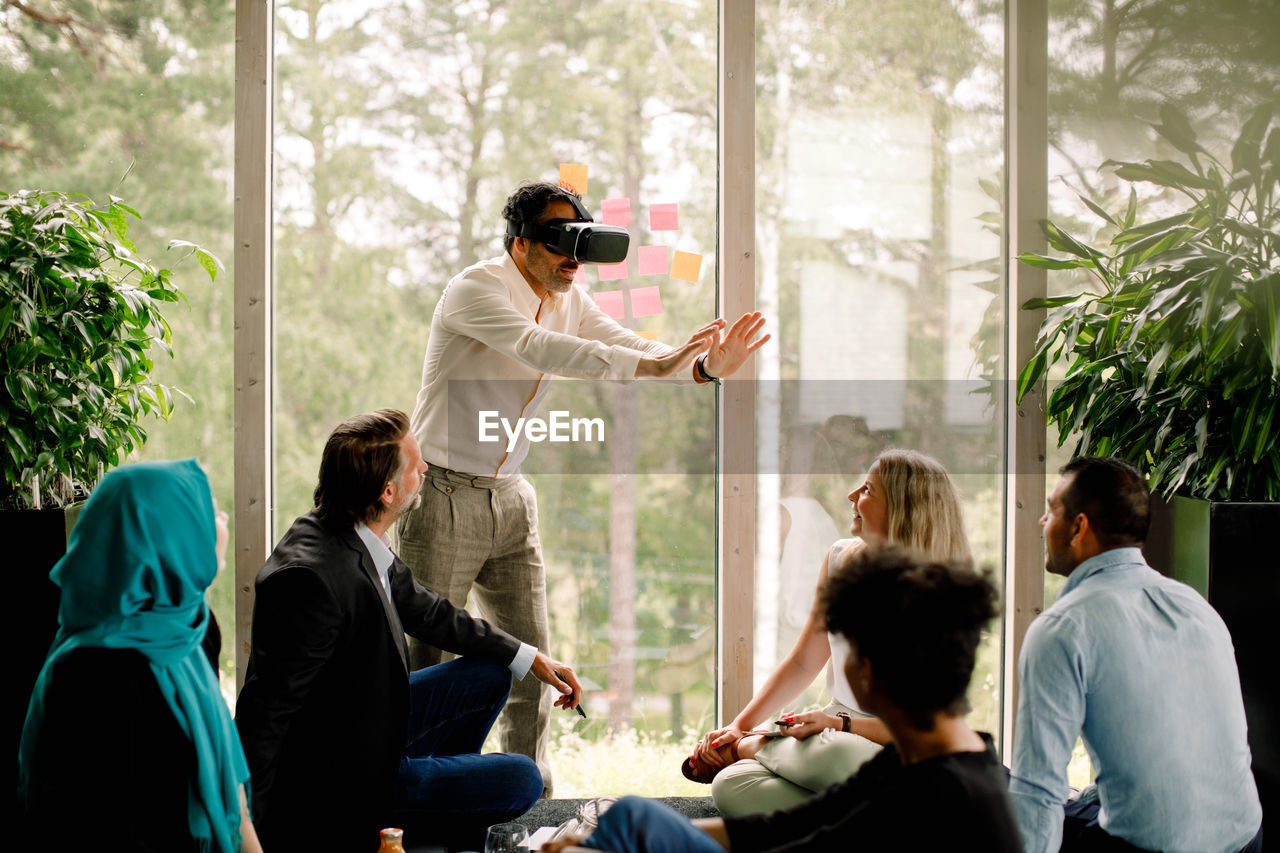 Businessman wearing virtual reality simulator during conference with colleagues at convention center