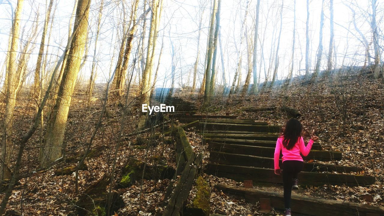 WOMAN STANDING ON TREE TRUNK