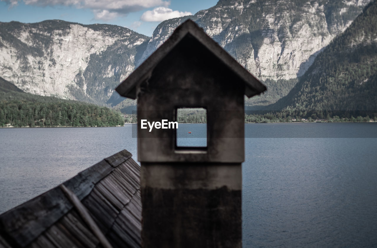 Built structure by lake against mountains