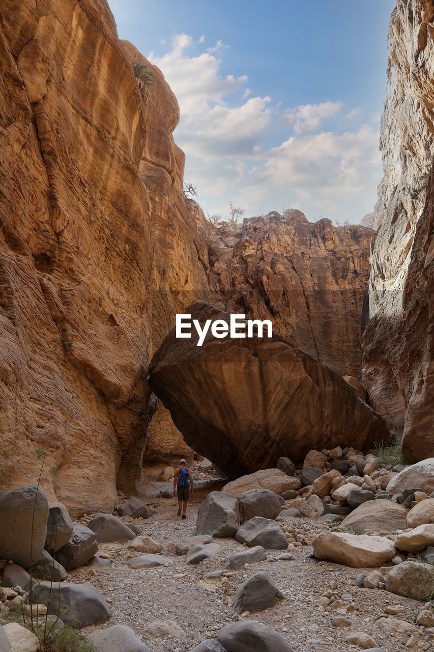 Man with backpack walking on wadi ghuweir canyon, jordan