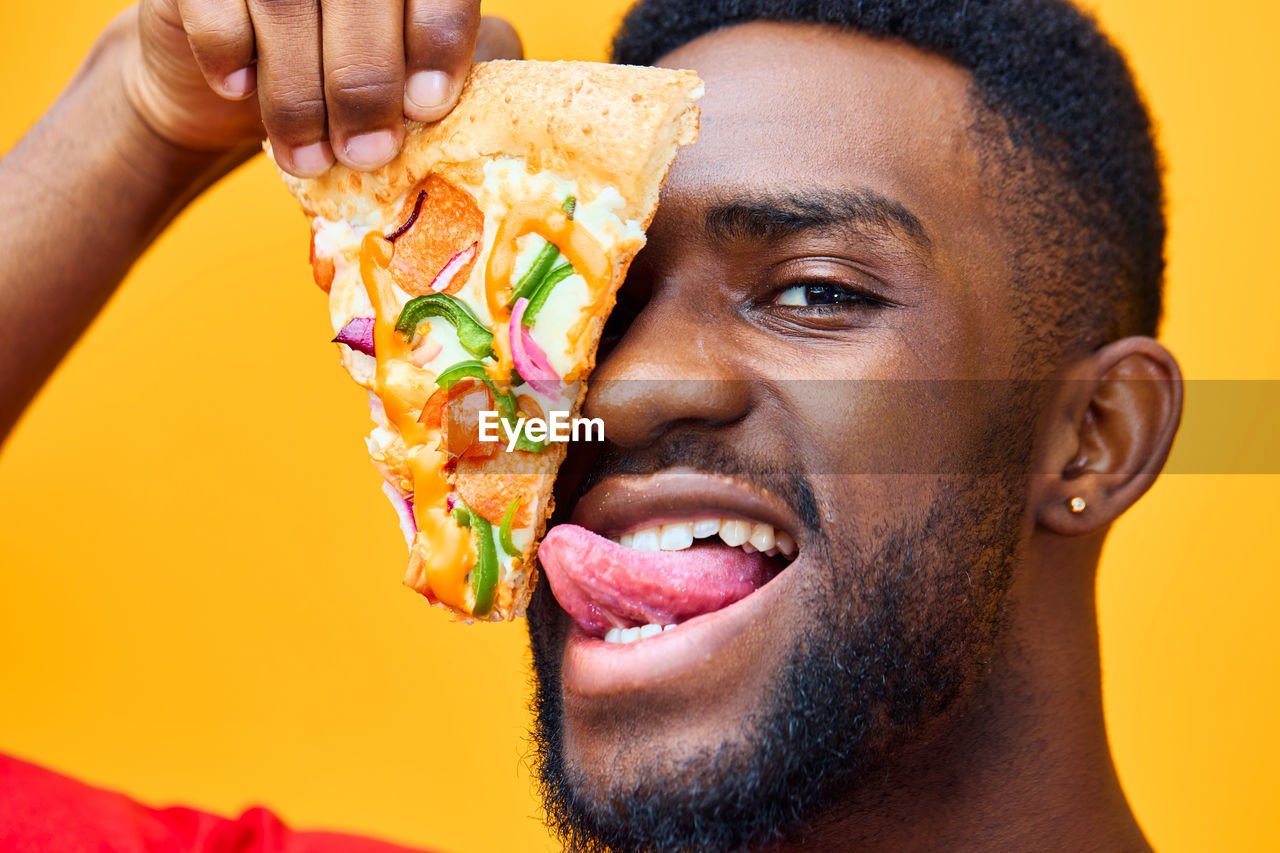 close-up of man holding food against yellow background