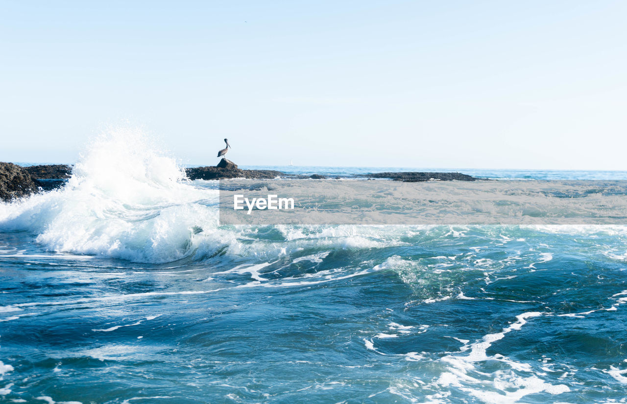 SCENIC VIEW OF SEA WAVES AGAINST CLEAR SKY