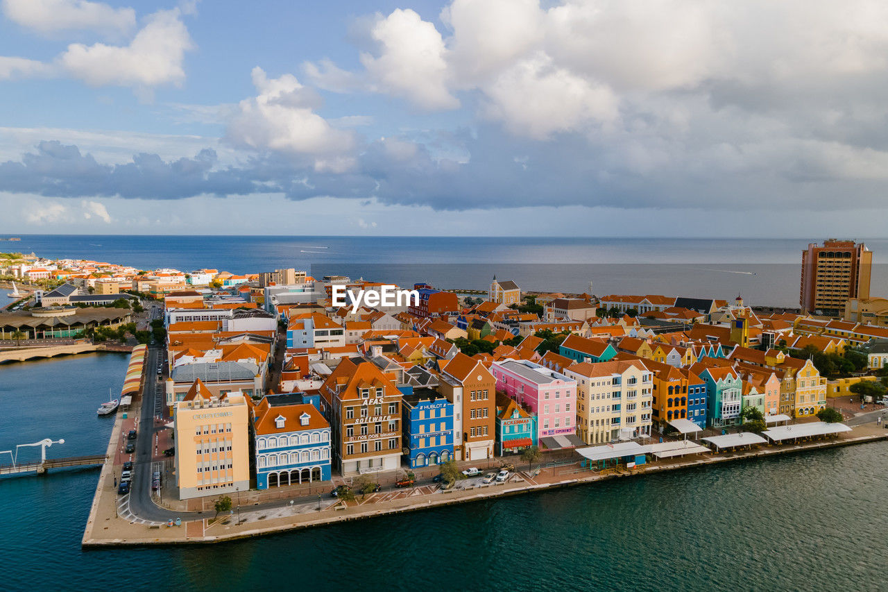 high angle view of cityscape by sea against sky