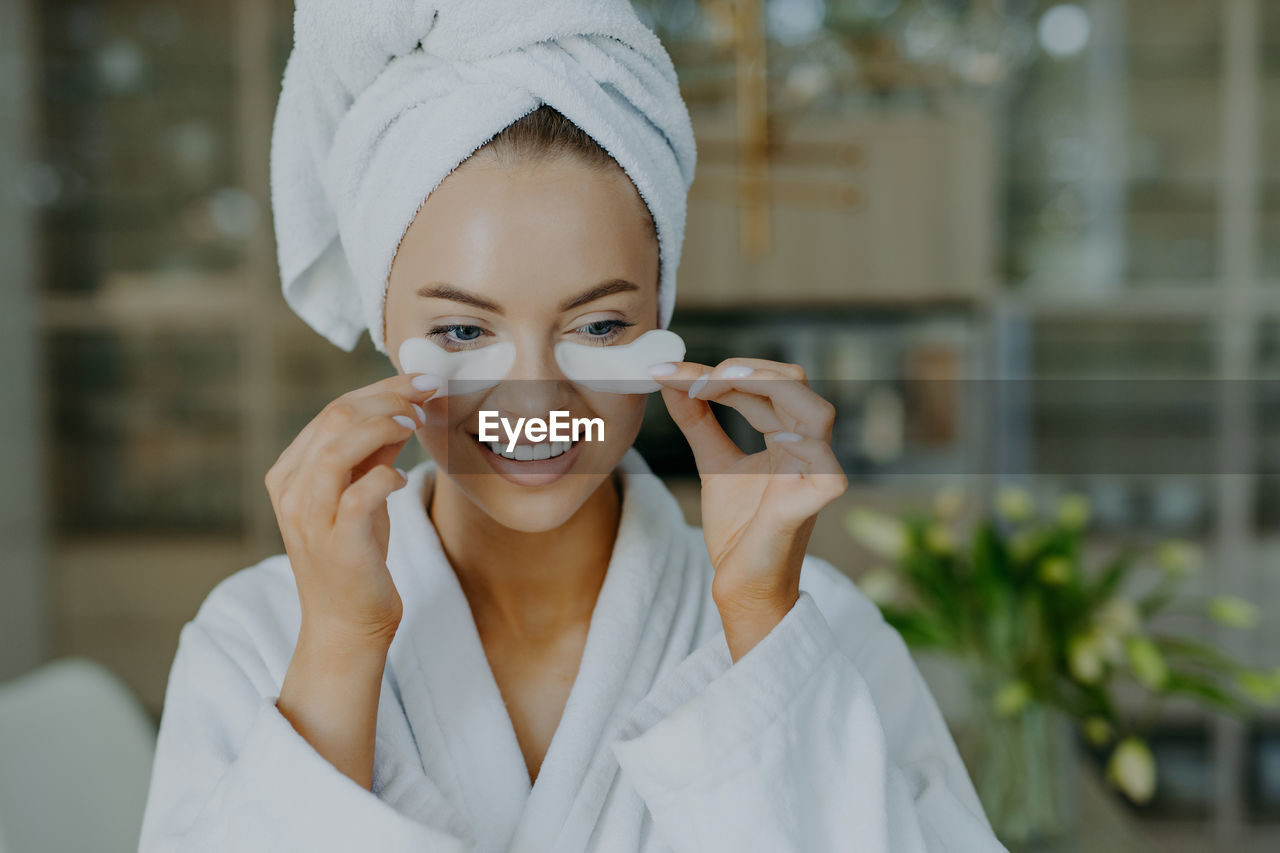 Young smiling woman holding medical eye patches at home