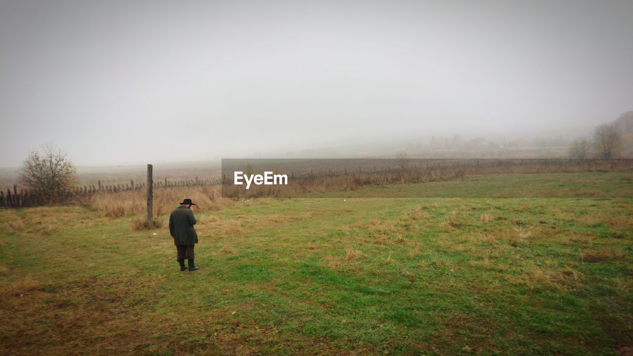 Rear view of man walking on field