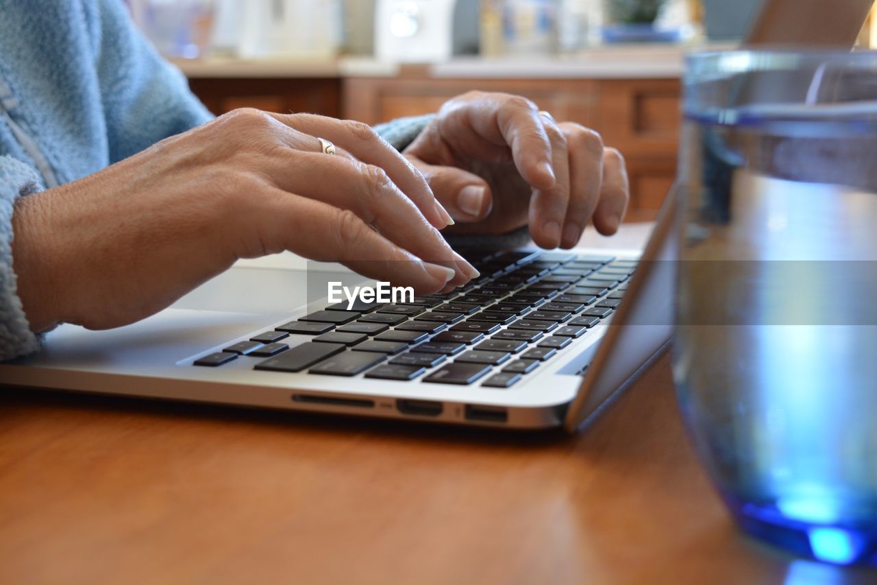 Midsection of woman using laptop on desk