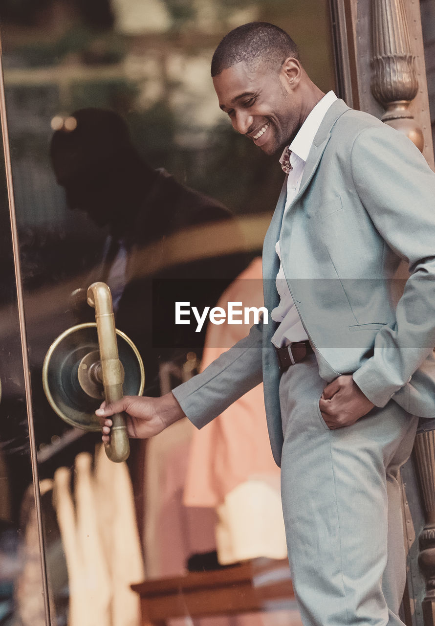 Businessman holding handle of door while standing outdoors