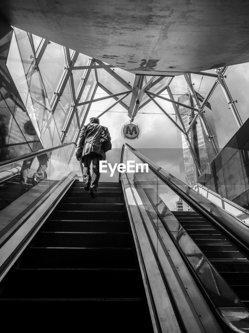 Low angle view of man moving up on escalator in subway station