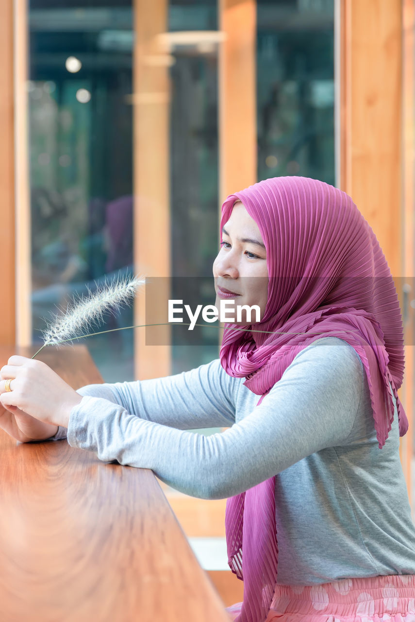 Beautiful smiling woman wearing hijab sitting outdoors