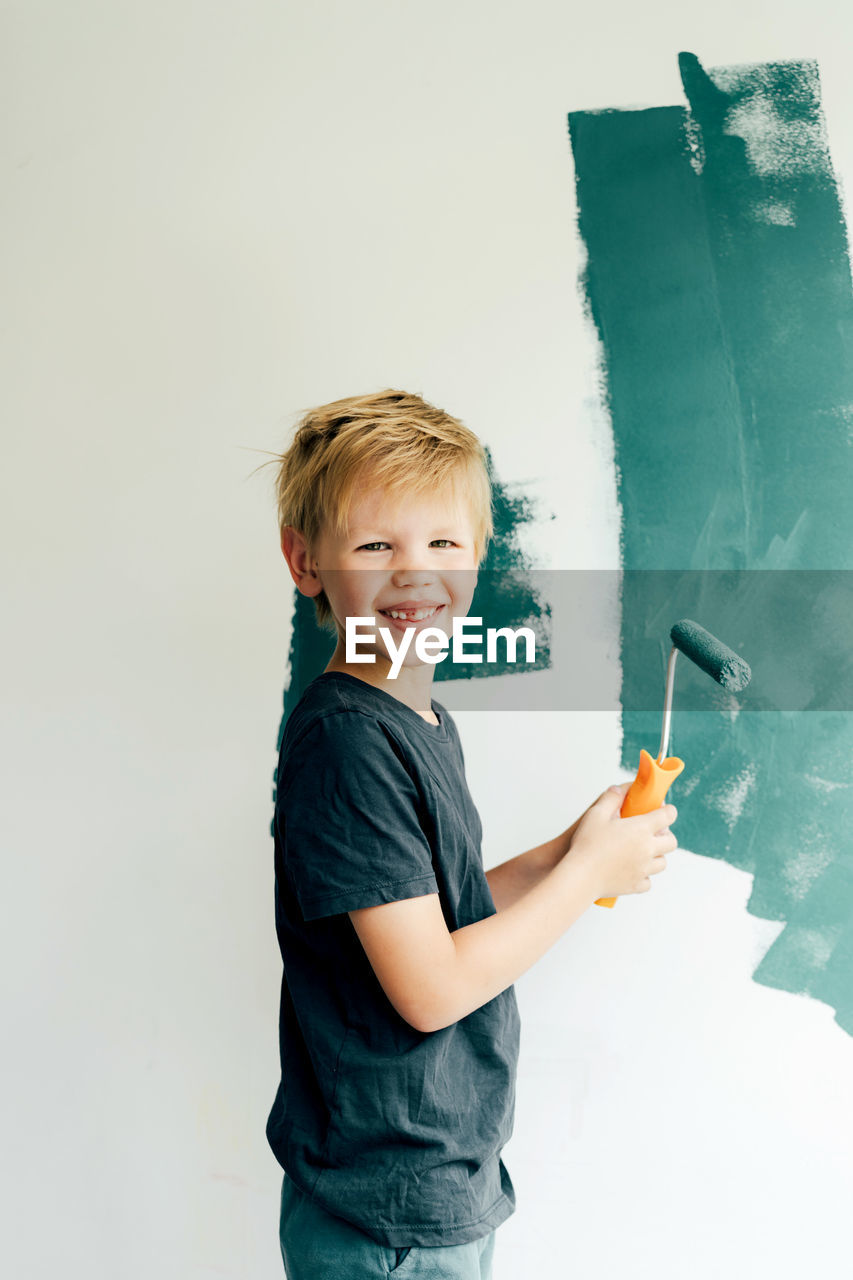 Portrait of boy painting wall at home