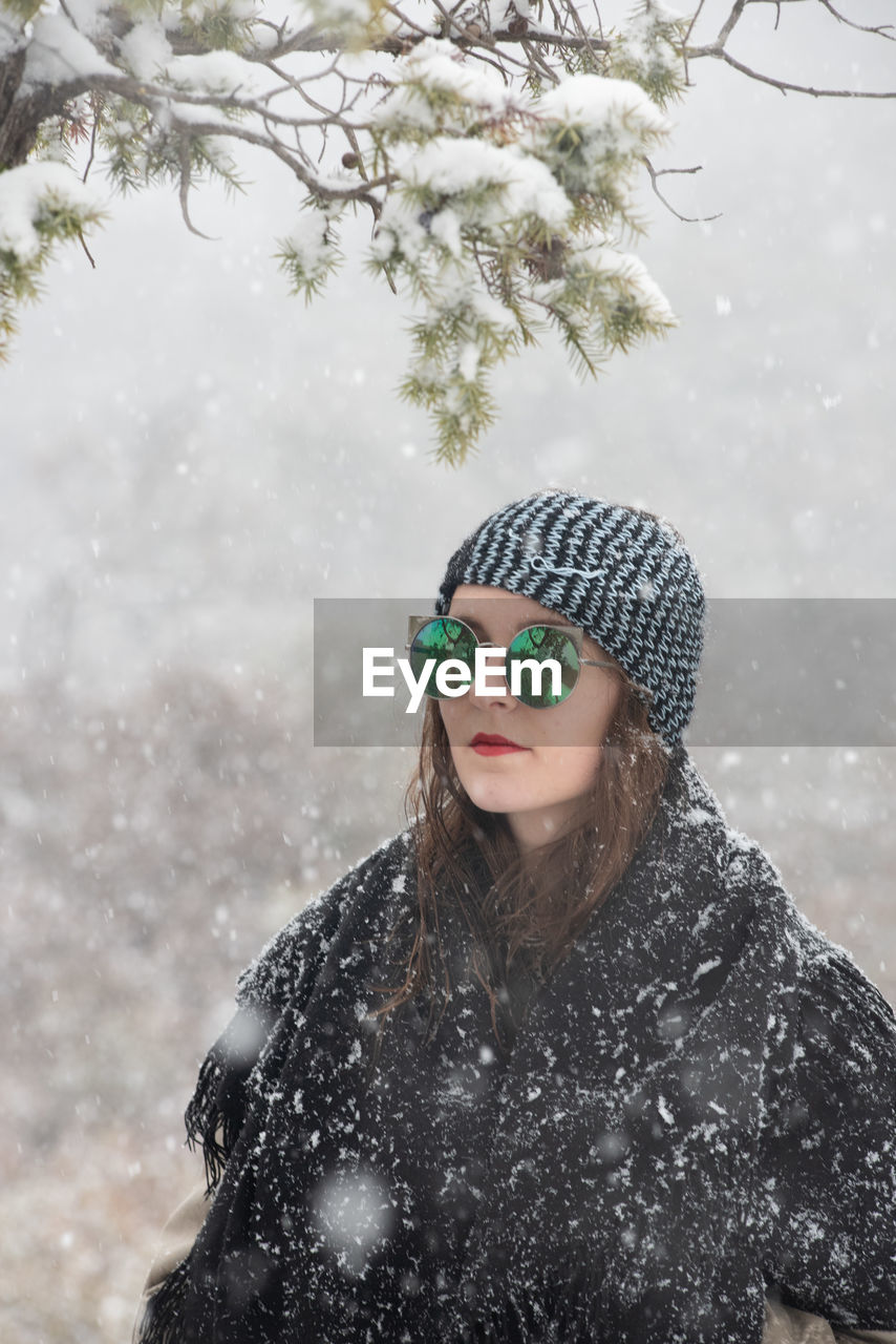 PORTRAIT OF YOUNG WOMAN WEARING HAT AGAINST TREES