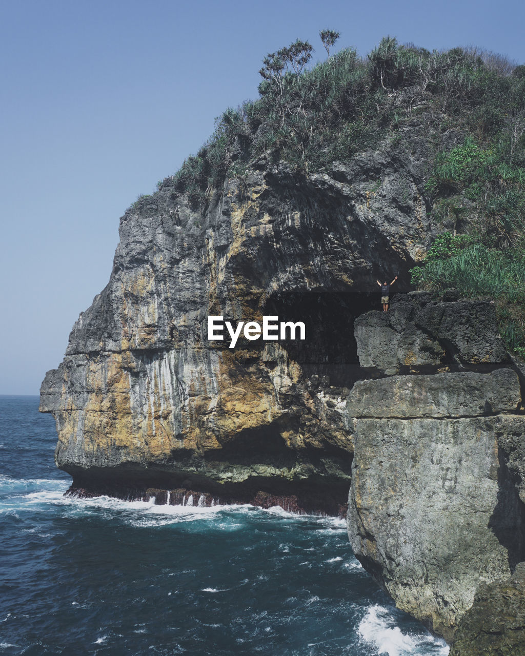 Rock formation in sea against clear sky