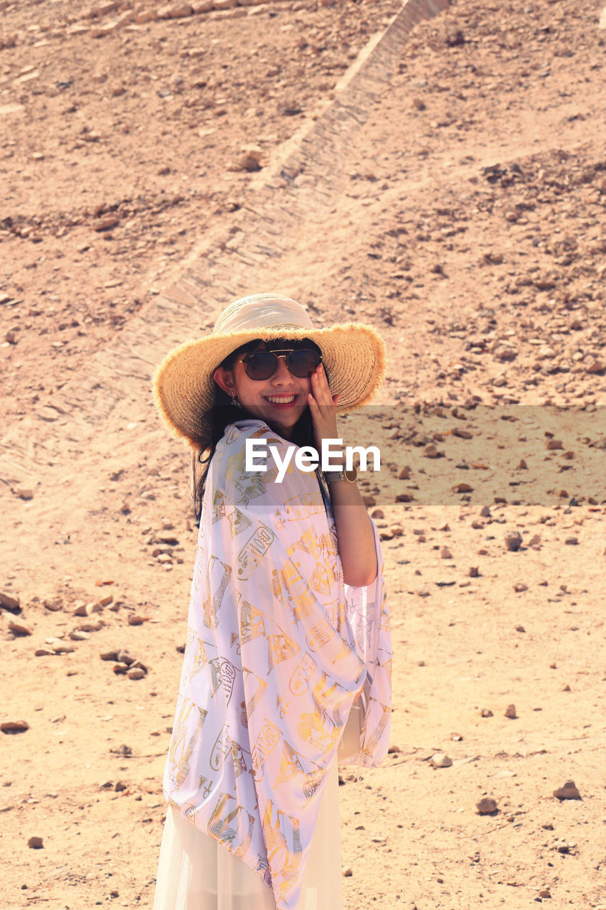 Young woman wearing hat standing at desert 