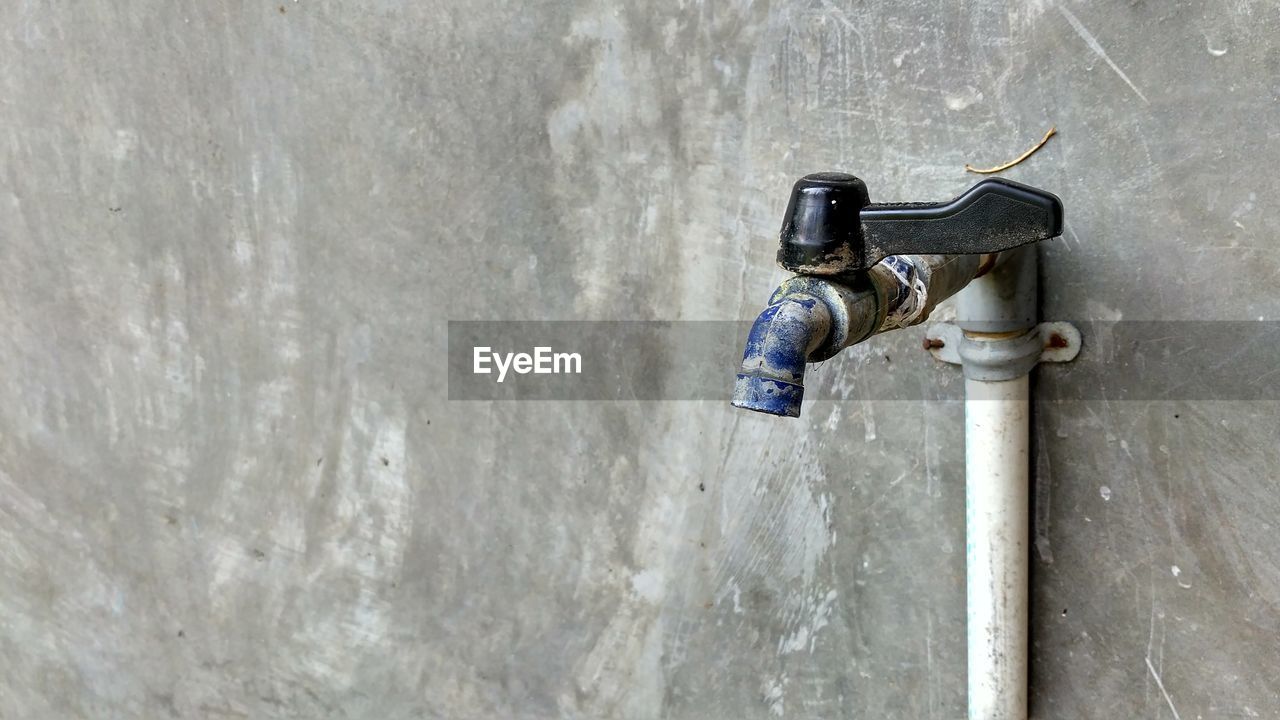 CLOSE-UP OF OLD FAUCET ON WALL