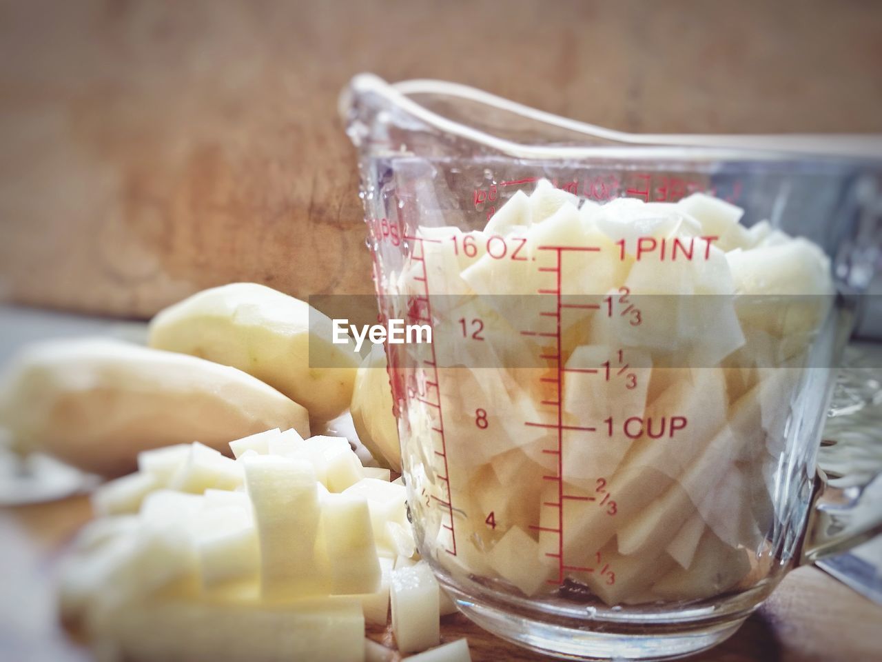 Close-up of chopped potatoes in liquid measure on table