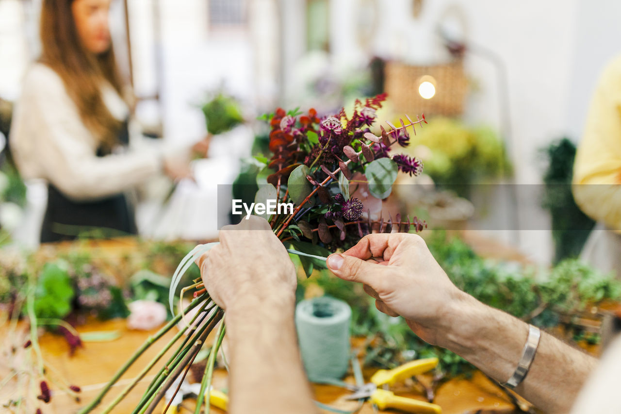 Hands of florist tying plants at flower shop