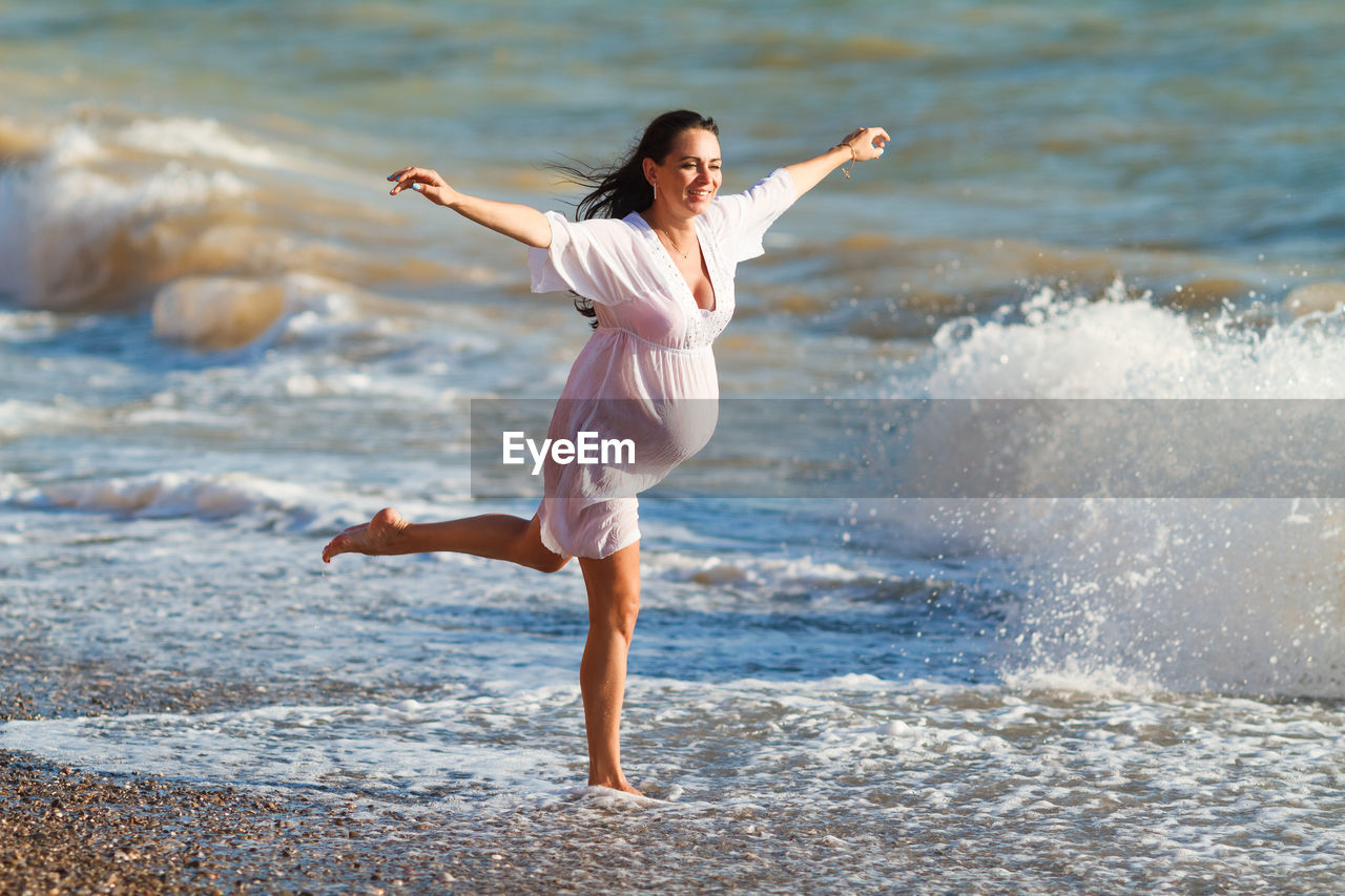Pregnant woman is jumping on beach. cheerful pregnant woman runs on seashore.