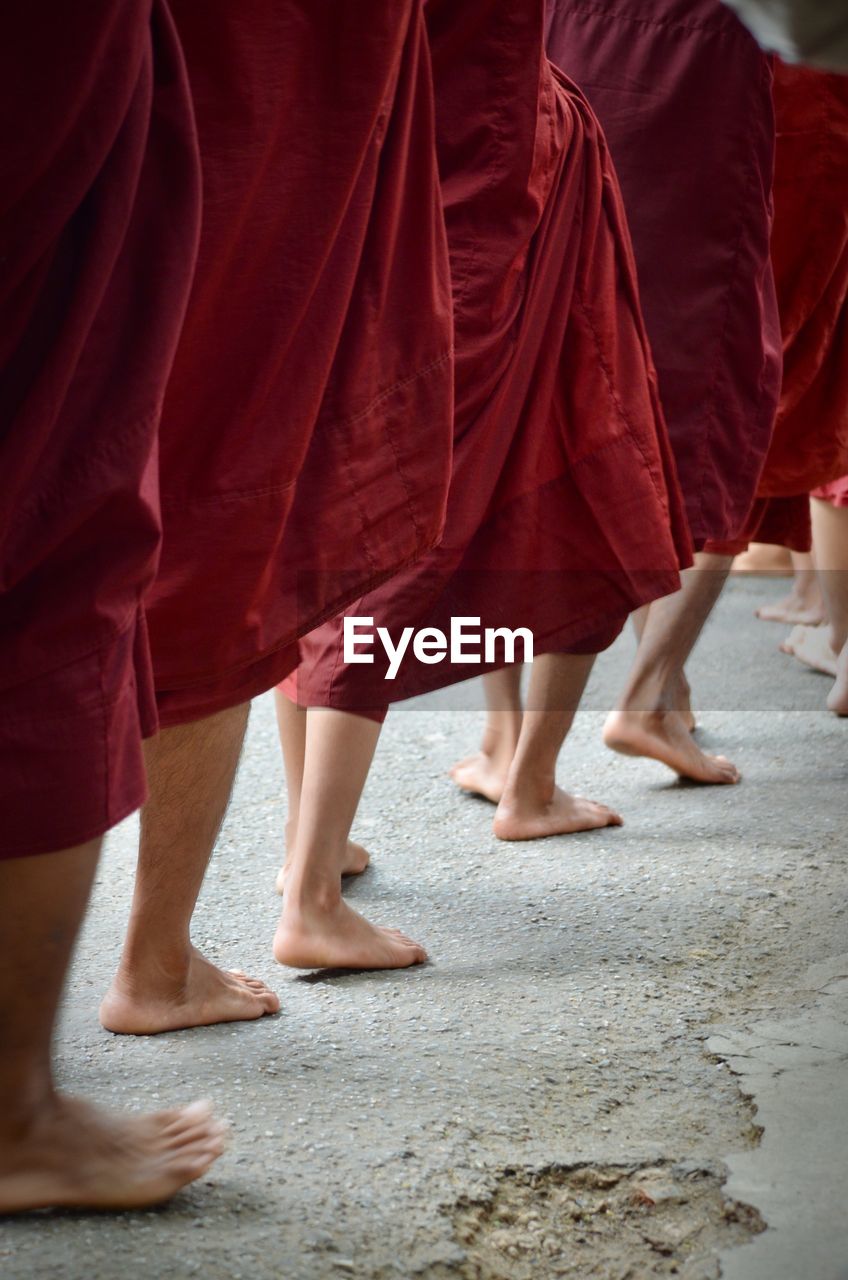 Low section of monks walking on footpath