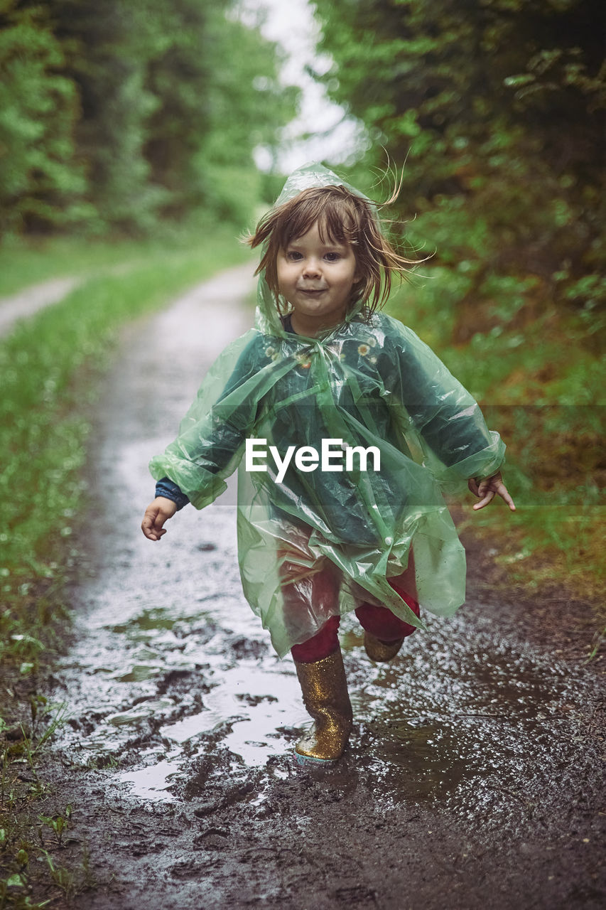 Charming child in a raincoat in the evening forest in denmark