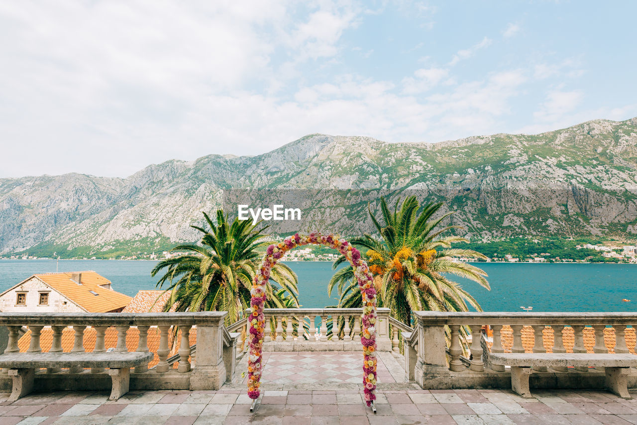 PALM TREES AGAINST SEA AND MOUNTAINS AGAINST SKY