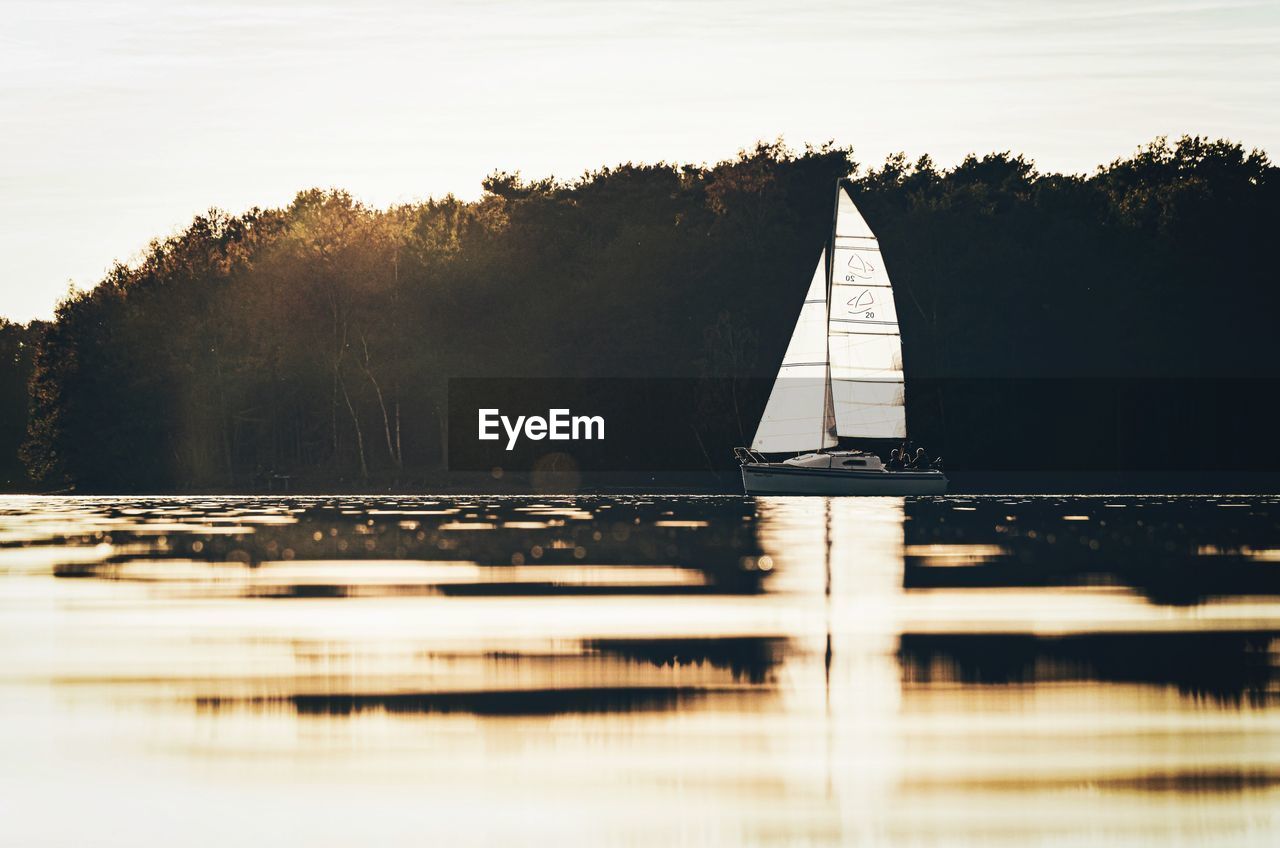 Scenic view of lake with boat against sky during sunset