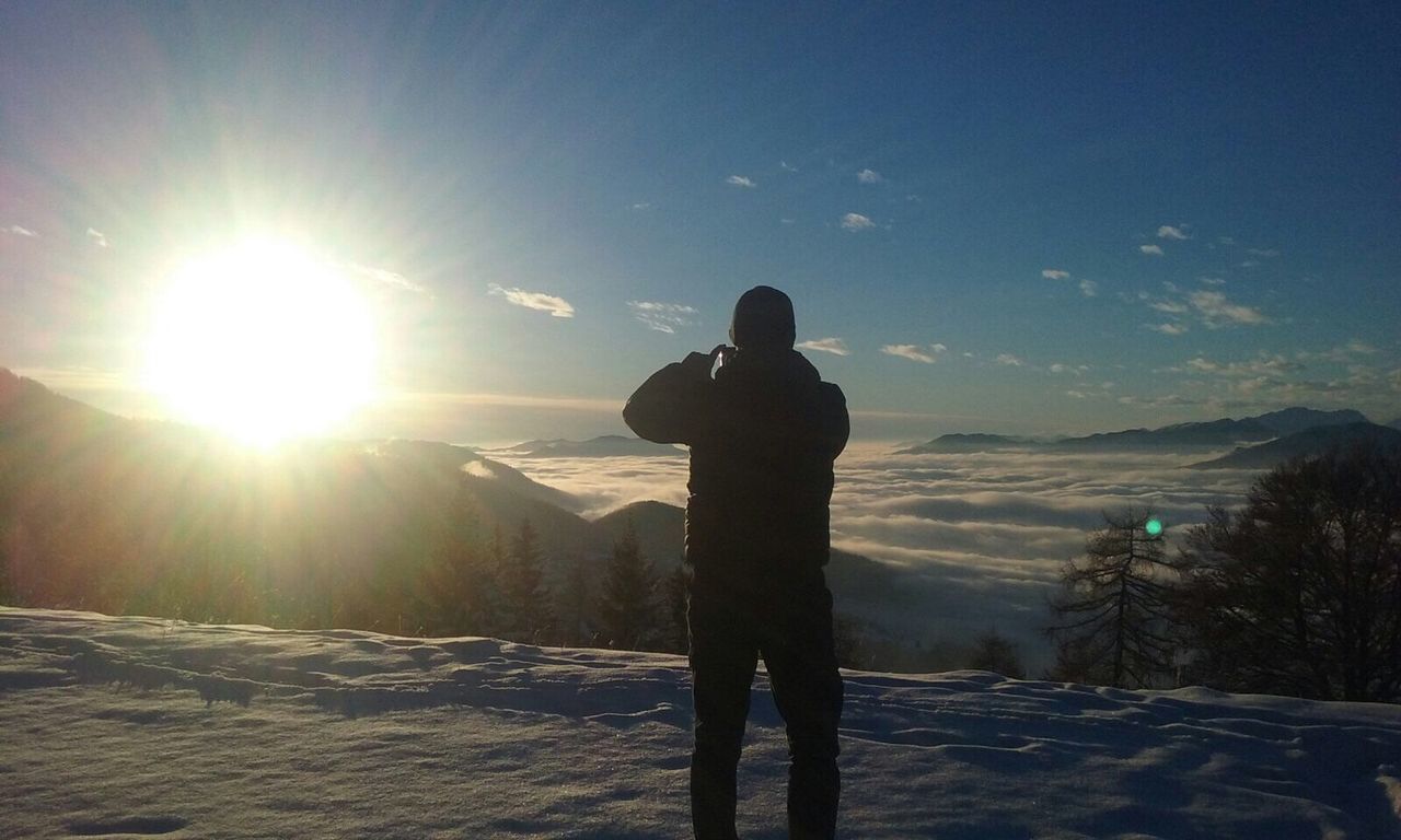 Rear view of man photographing sunset during winter