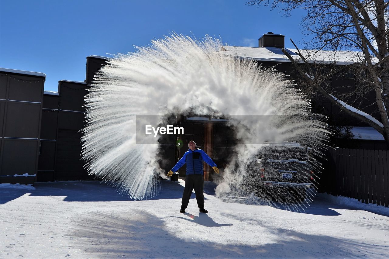 Full length of man throwing snow while standing outdoors