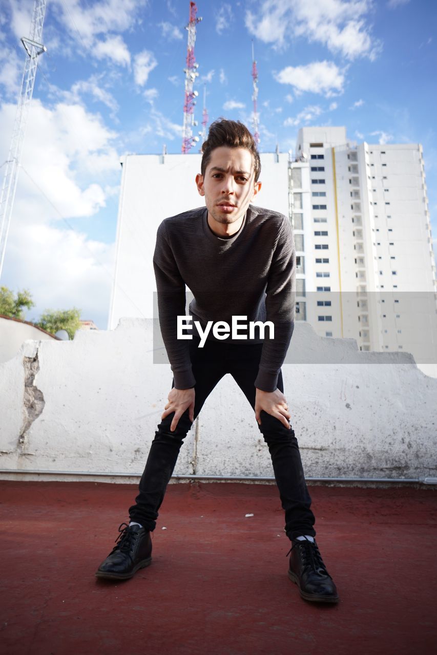 Portrait of young man standing against buildings