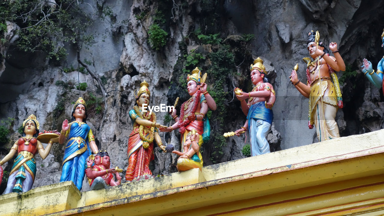 Low angle view of statues on temple roof against rock formations