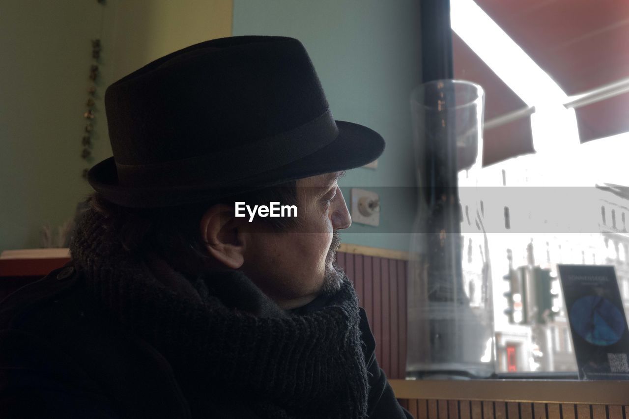 one person, hat, adult, clothing, headshot, indoors, fedora, portrait, looking, lifestyles, person, mature adult, black, fashion accessory, men, day, side view, women, looking away