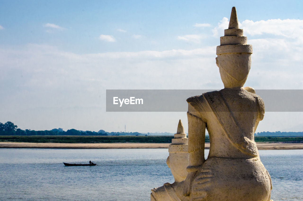 Buddha statues by river against sky