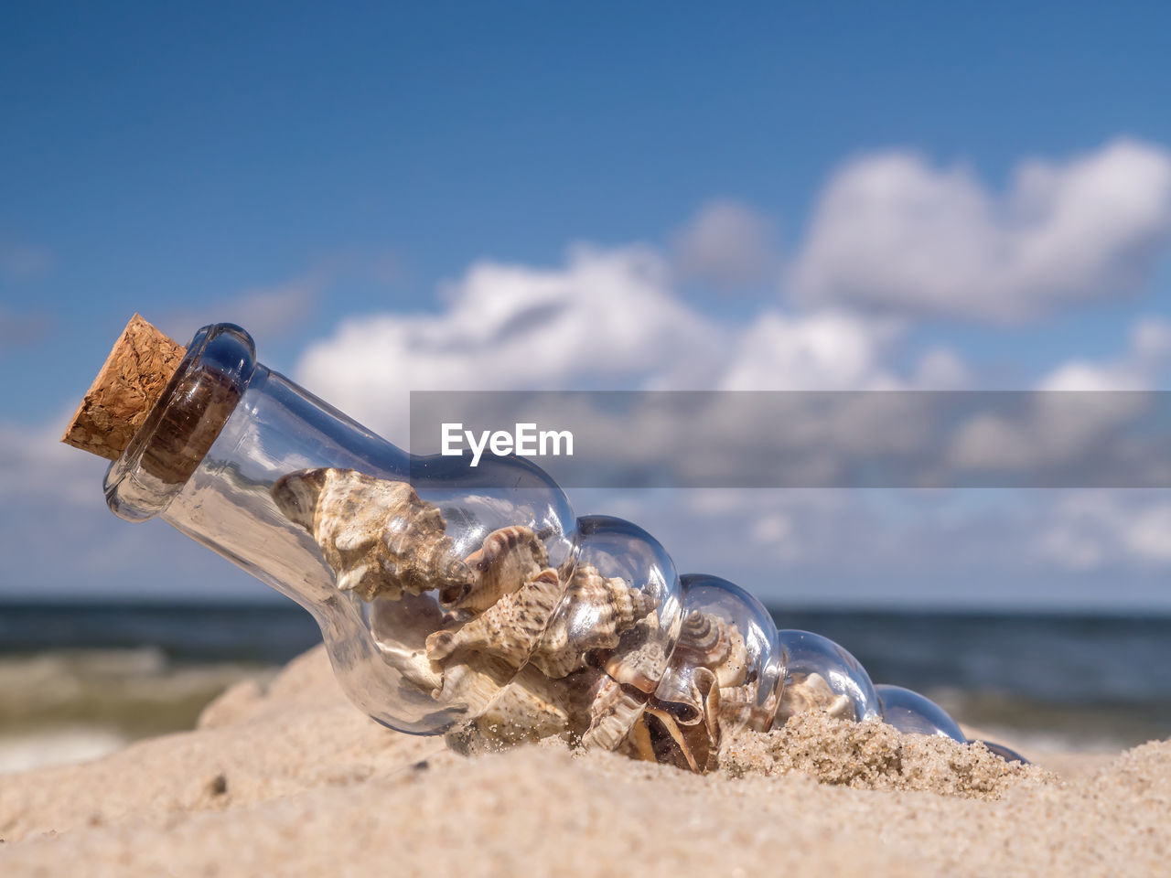 Close-up of bottle on beach against sky