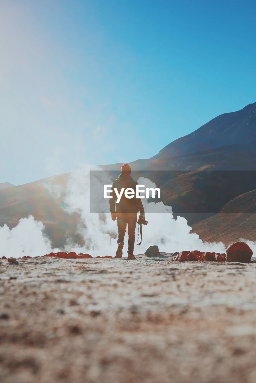 Smoke emitting by silhouette man standing at atacama desert against clear blue sky