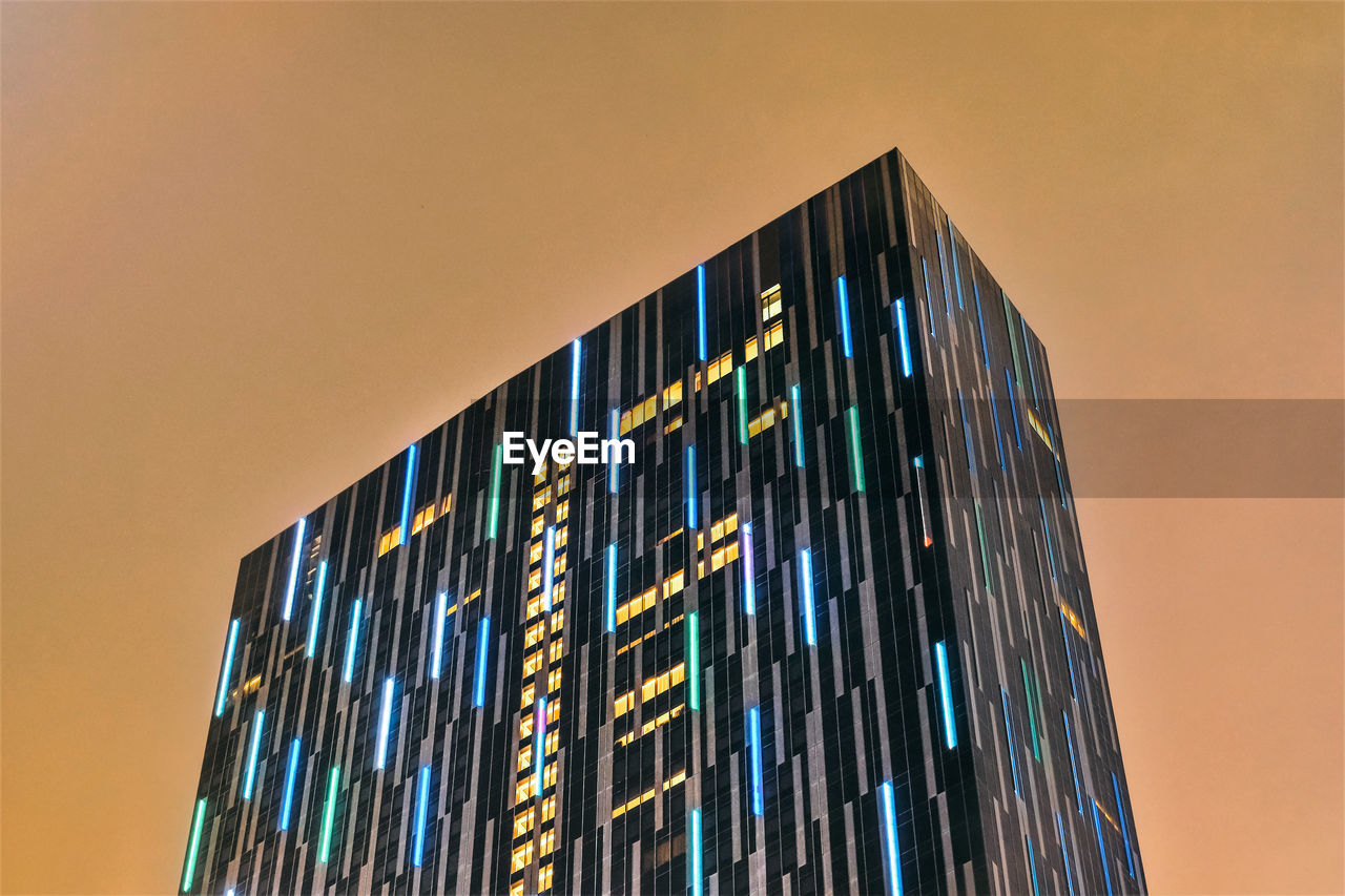 Low angle view of illuminated modern building against sky at dusk