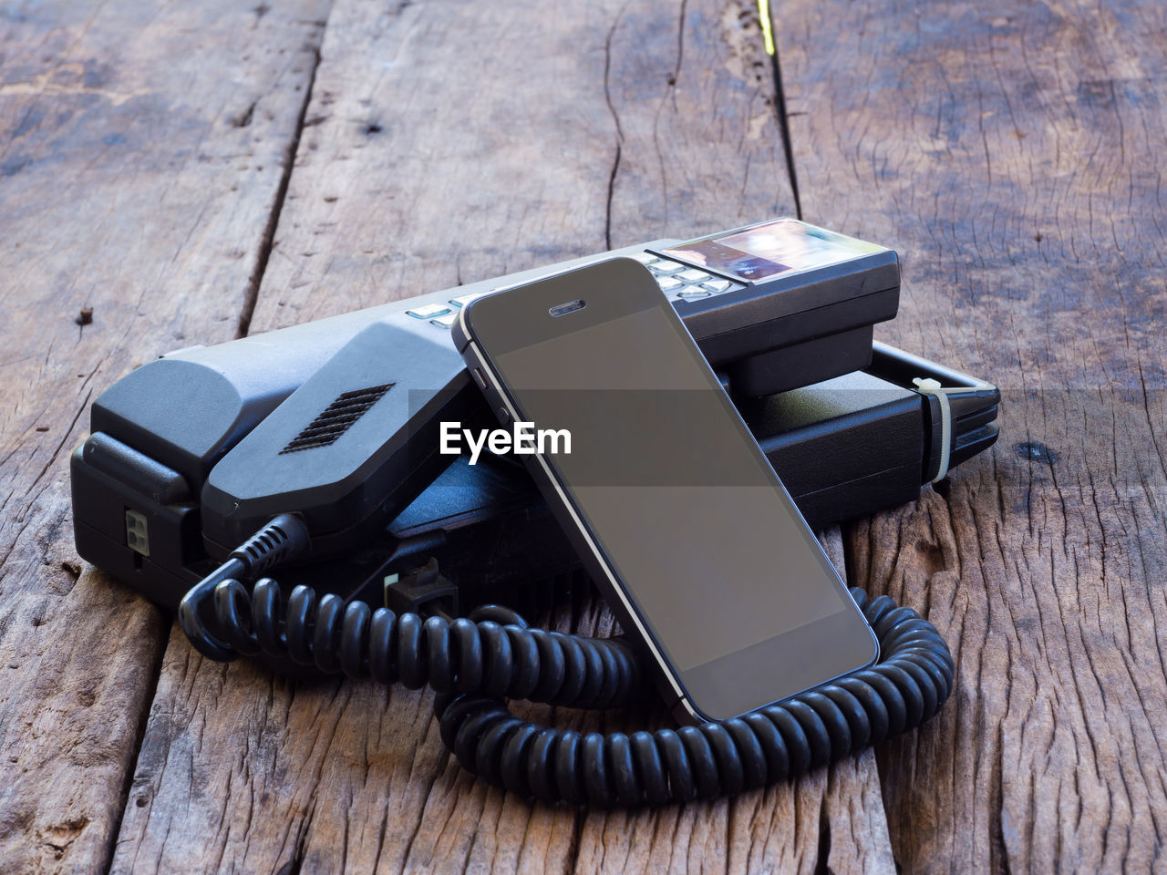 Telephone with mobile phone on wooden table