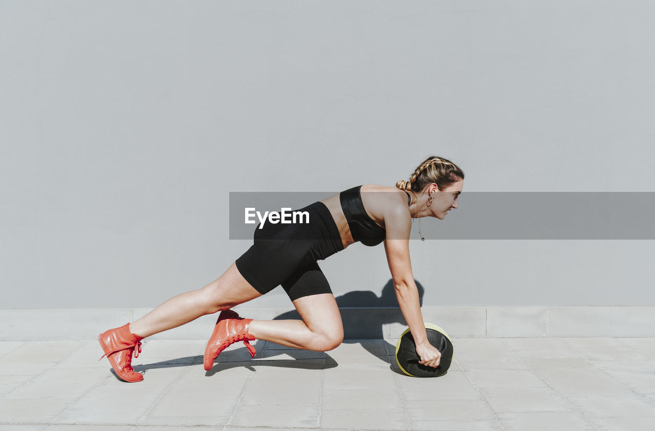 Young athlete with medicine ball exercising on sunny day