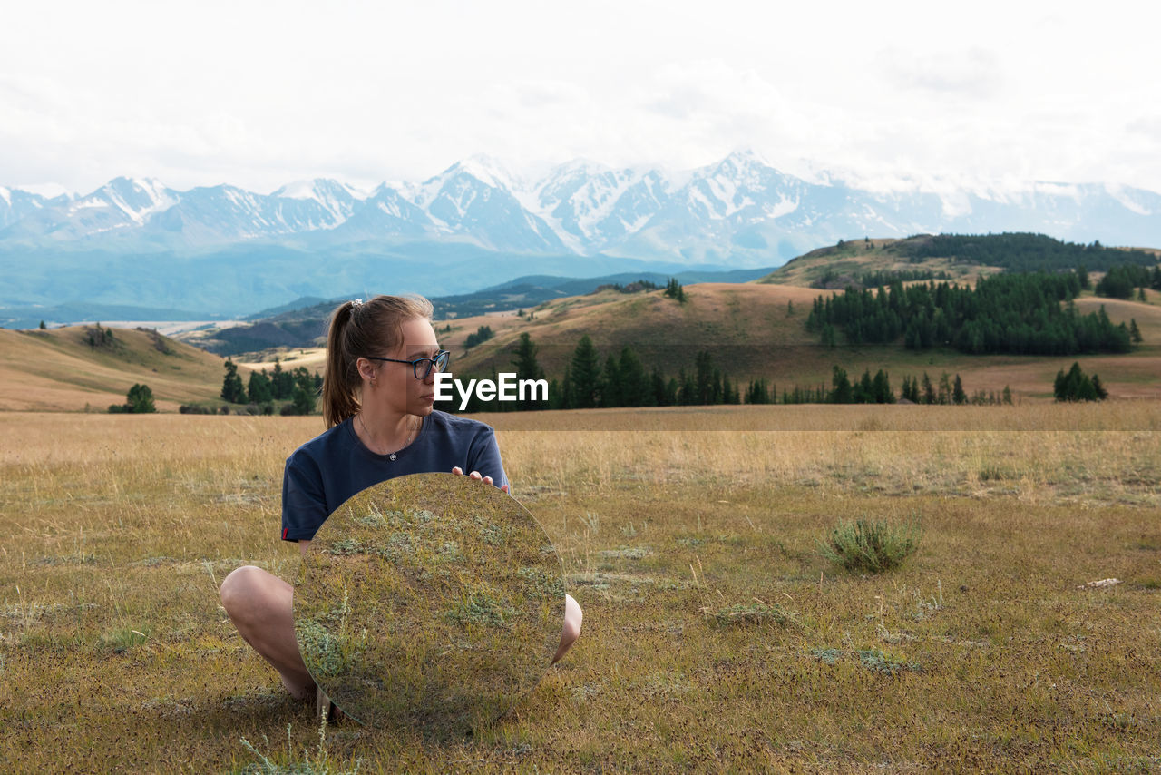 WOMAN ON FIELD AGAINST MOUNTAIN